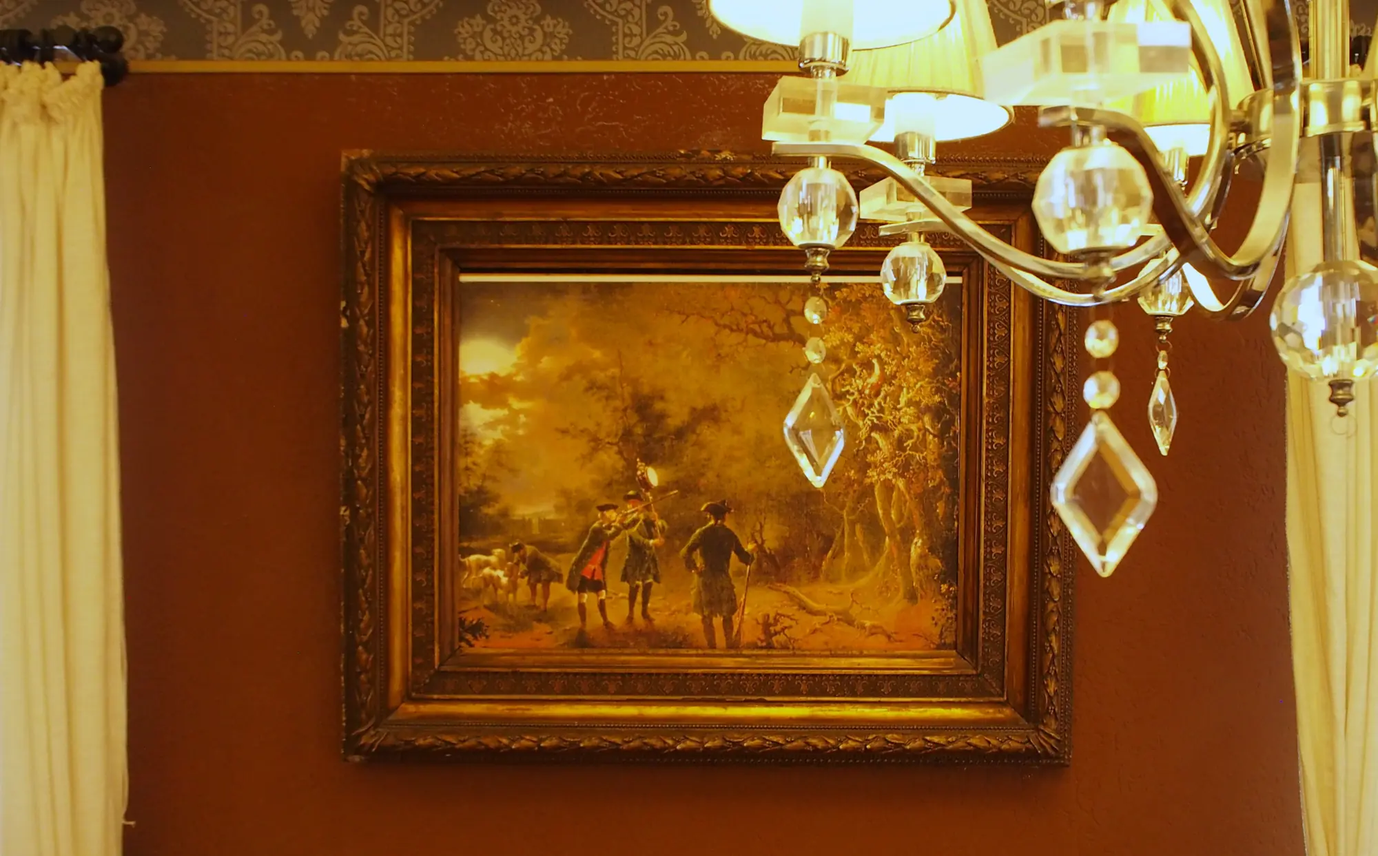 Gemälde von jägern aus dem 17 jahrhundert auf roter wand mit kronleuchter