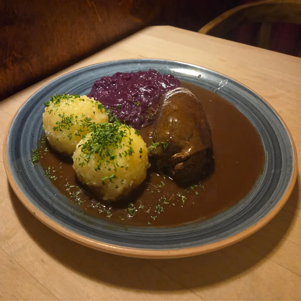 Rinderroulade mit Thüringer Klößen und Rotkraut auf Holztisch in Weimarer Restaurant Jagemanns